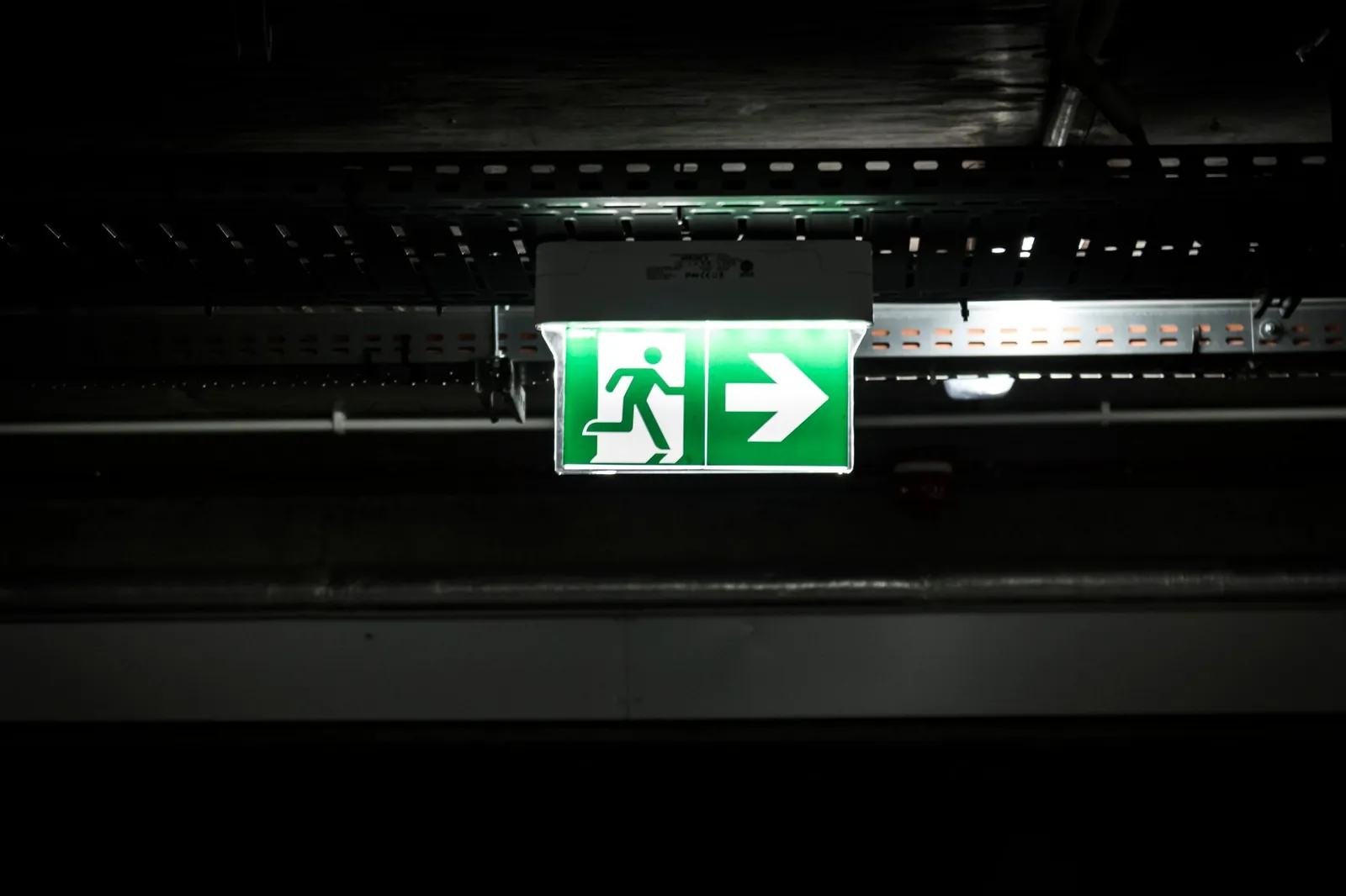 Illuminated green fire exit sign with a running figure and arrow