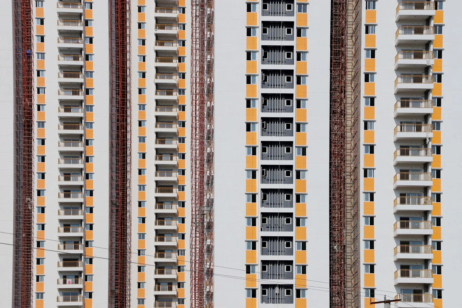 Close-up of a modern high-rise residential building facade with balconies and scaffolding.