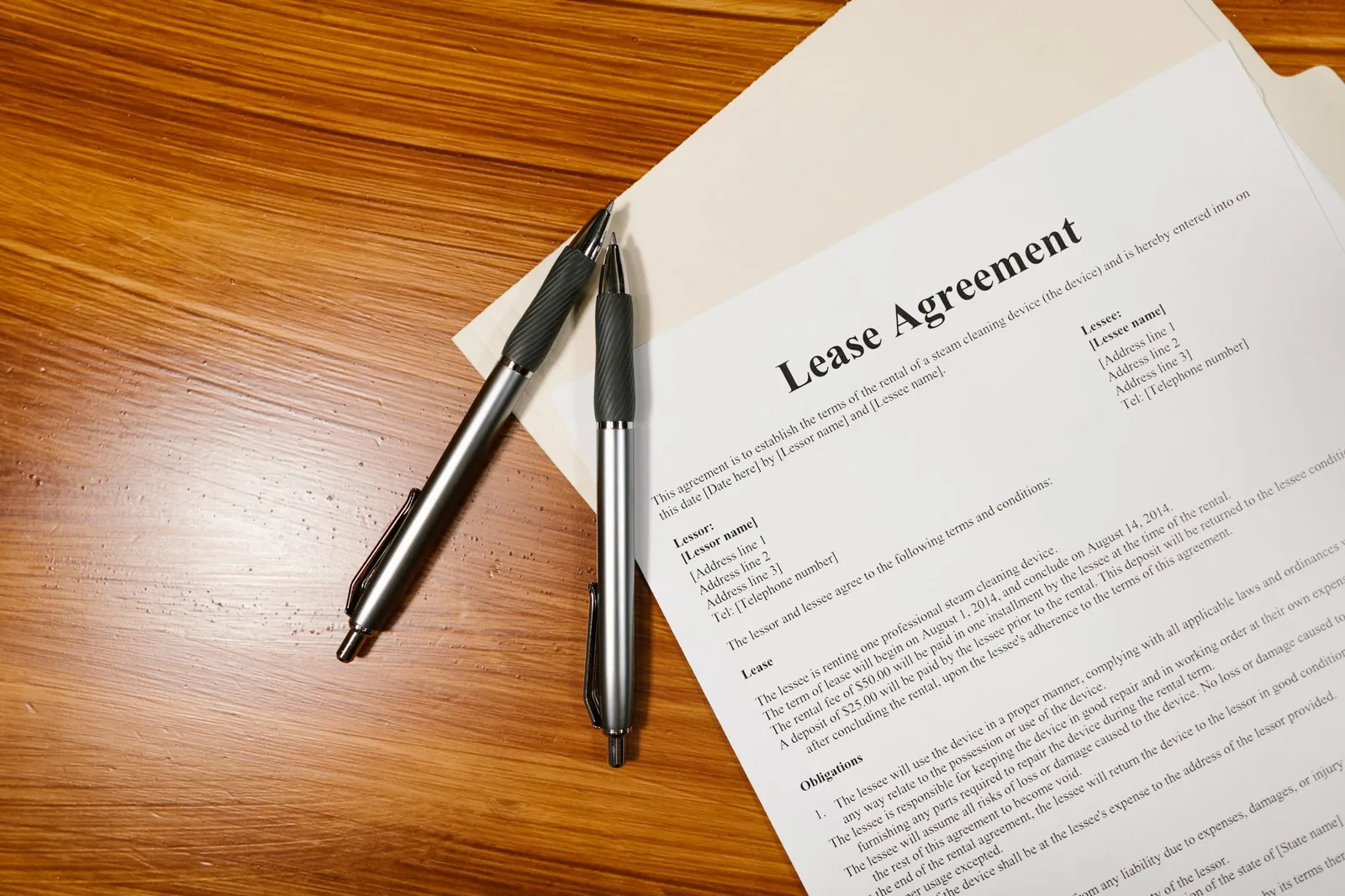 High-angle view of a lease agreement and pens on a wooden desk.