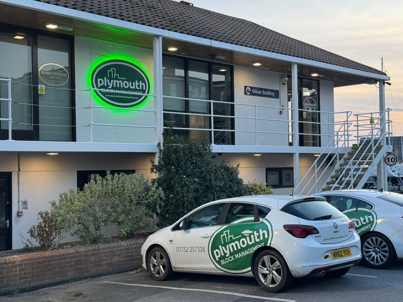 The Ocean Building at Queen Anne’s Battery, with the illuminated Plymouth Block Management sign and two PBM liveried cars outside